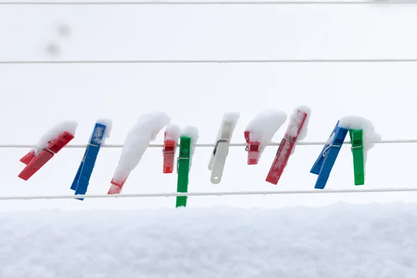 Colorful clips washing laundry covered snow strip rope outdoor. Winter. — Stock Photo, Image