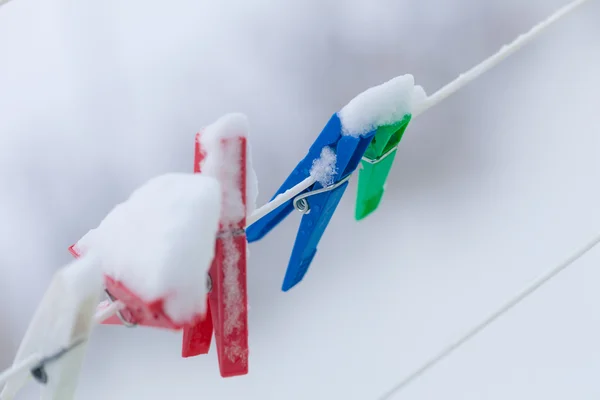 Colorful clips washing laundry covered snow strip rope outdoor. Winter.