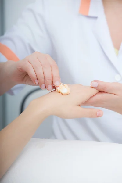 Kosmetikerin, die die Hände der Kunden mit Feuchtigkeitscreme eincremt. Schönheitssalon — Stockfoto