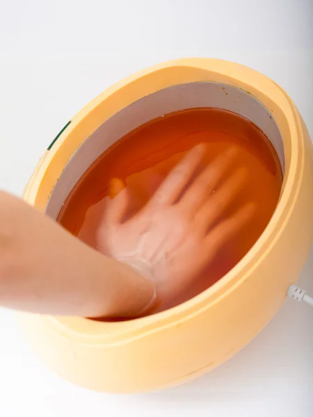 Vrouwelijke hand en oranje paraffine bowl. vrouw in beauty salon — Stockfoto