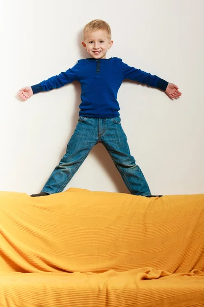 Menino criança criança pré-escolar de pé no encosto do sofá interior — Fotografia de Stock