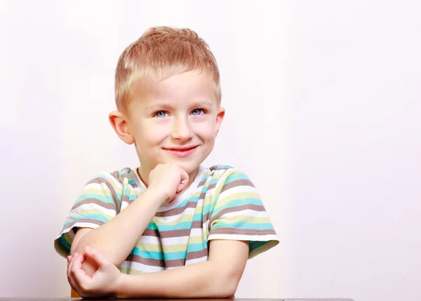 Portret roześmiany szczęśliwy blond chłopiec dziecko przy stole — Zdjęcie stockowe