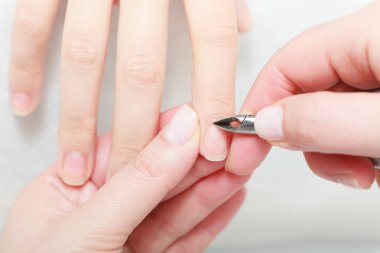 Beautician trimming cuticles of female client in beauty salon clipart