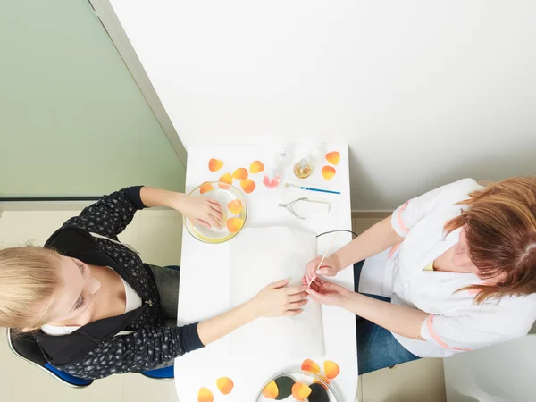 Schoonheidsspecialiste schoonmaken nagelriemen handen vrouwelijke client. Beauty salon. — Stockfoto