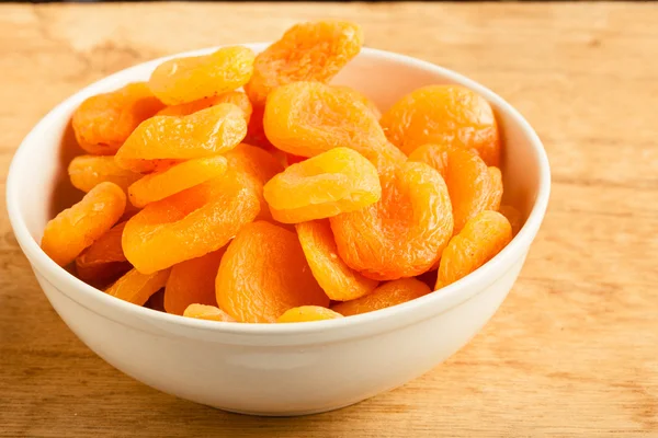 Bowl of dried apricots on wooden table background. — Stock Photo, Image