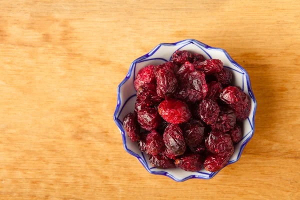 Kost hälsosam mat. torkade tranbär i skål på träbord bakgrund — Stockfoto