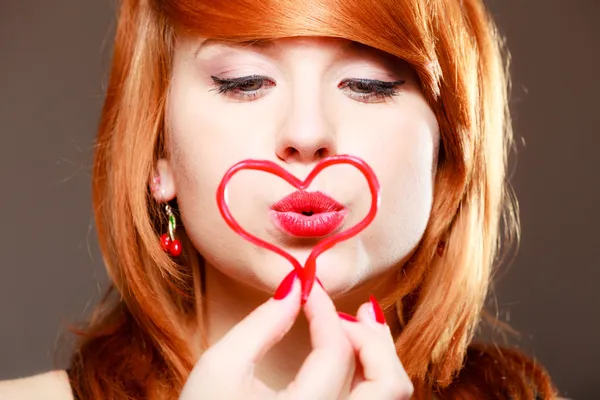 Redhaired κοπέλα που κρατά κόκκινη καρδιά αγάπη φυσούσε φιλί. ημέρα του Αγίου Βαλεντίνου. — Φωτογραφία Αρχείου