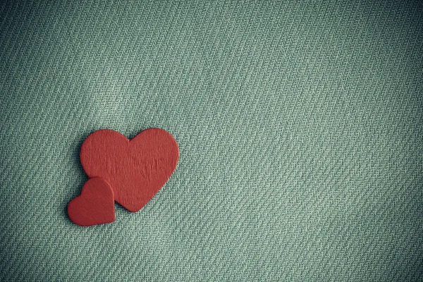 Coeurs décoratifs en bois rouge sur fond de tissu gris . — Photo