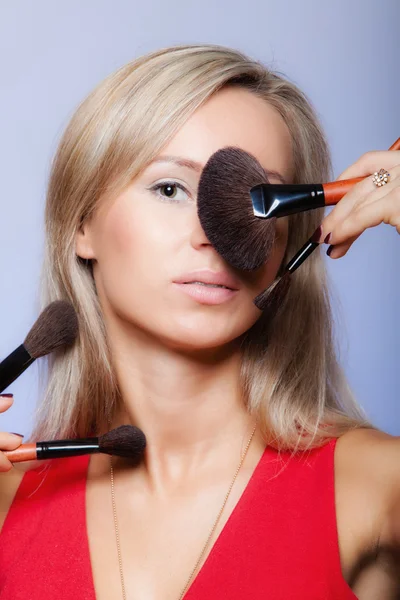 Procedimentos de beleza, mulher mantém pincéis de maquiagem perto do rosto . — Fotografia de Stock