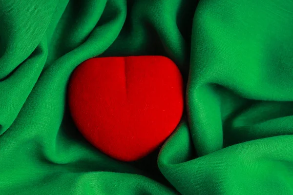 Caja de joyas roja regalo en forma de corazón en tela verde tela ondulada —  Fotos de Stock