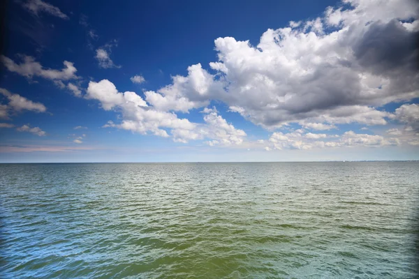 Cloudy blue sky above a surface of the sea — Stock Photo, Image