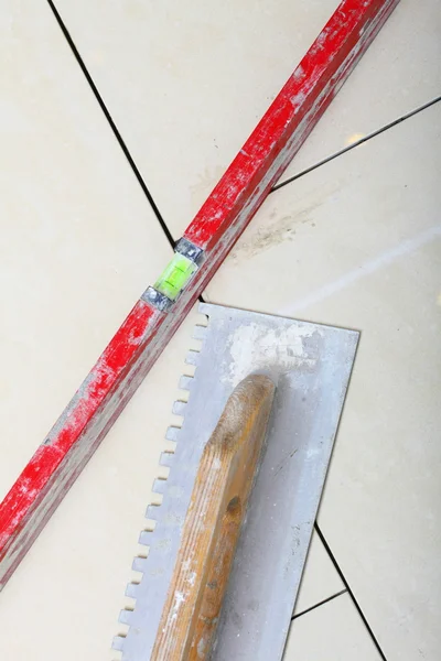 Building work tool notched trowel level on tile floor surface — Stock Photo, Image