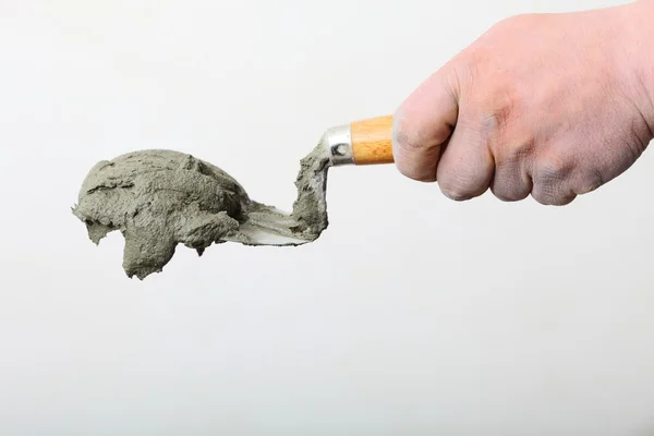 Hand holding a bucket trowel with cement mortar — Stock Photo, Image