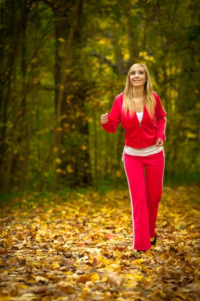 Blonde girl young woman running jogging in autumn fall forest park — Stock Photo, Image