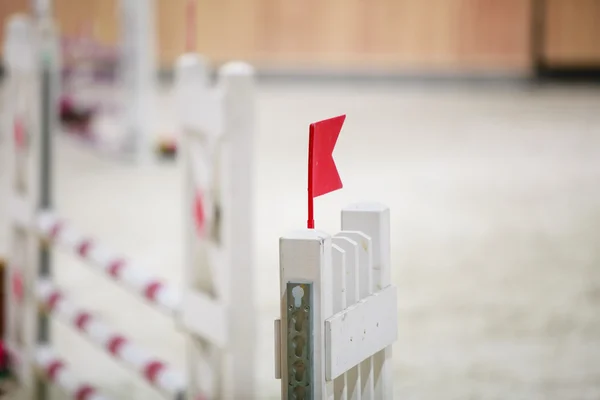 Lähikuva valkoinen este punaisella lipulla hyppäämiseen hevosia. Ratsastuskilpailu. — kuvapankkivalokuva