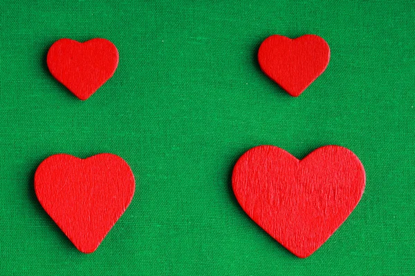 Corazones decorativos rojos de madera sobre fondo de tela verde —  Fotos de Stock