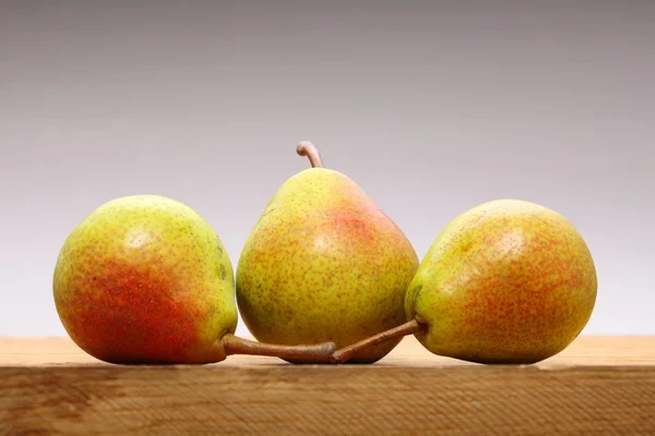 Três pêras frutas na mesa de madeira — Fotografia de Stock