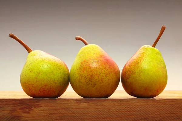 Três pêras frutas na mesa de madeira — Fotografia de Stock