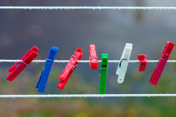 Pinzas de lavado coloridas en la tira al aire libre. Contexto. — Foto de Stock