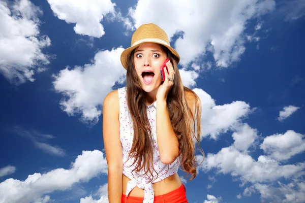 Chica emocional sorprendida hablando por teléfono móvil. Fondo del cielo . —  Fotos de Stock