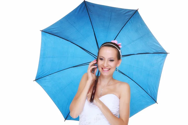 Dzień ślubu. panna młoda z niebieski parasol mówić na białym tle telefon — Zdjęcie stockowe
