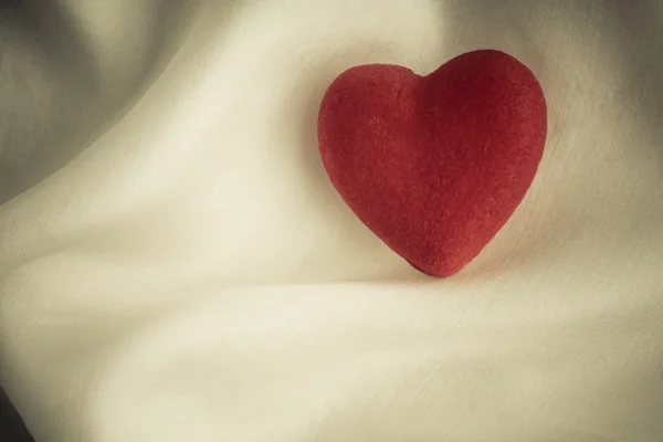 Coeur décoratif en bois rouge sur fond de soie blanche . — Photo