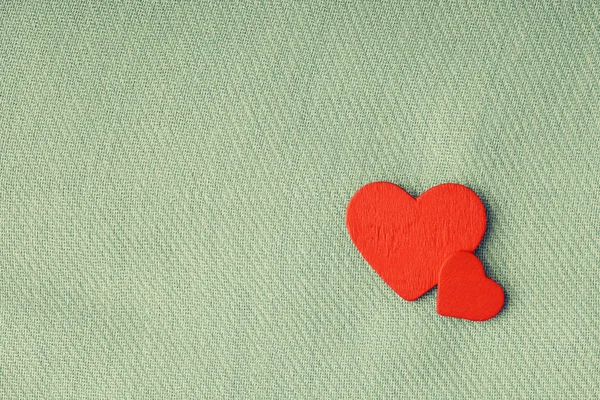 Red wooden decorative hearts on gray cloth background. Stock Picture