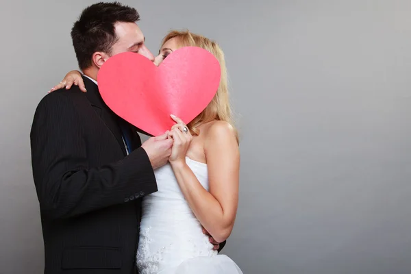 Noiva feliz e noivo beijando atrás coração vermelho — Fotografia de Stock