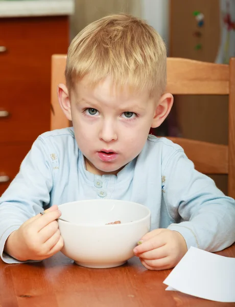 Niño niño comiendo hojuelas de maíz desayuno comida de la mañana en casa . — Foto de Stock