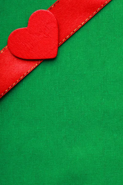 Corazón decorativo rojo de madera sobre fondo de tela verde . —  Fotos de Stock