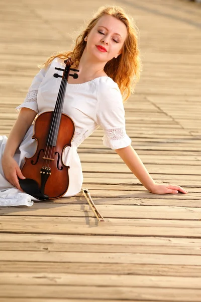 Блондинка со скрипкой на улице — стоковое фото