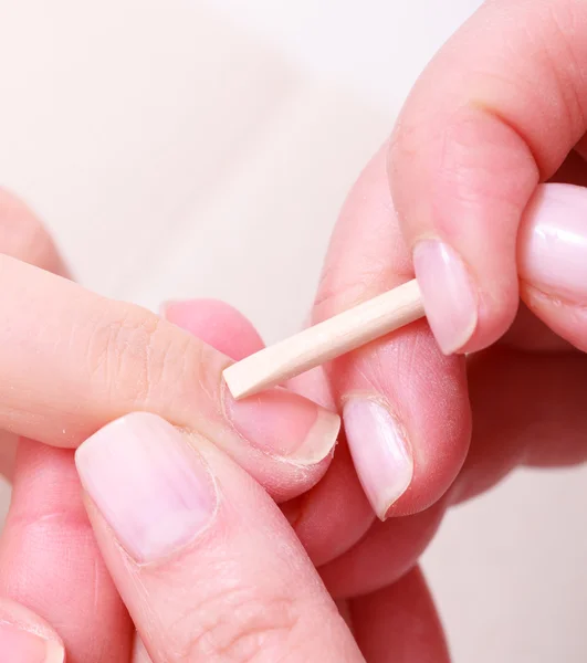 Kosmetikerin reinigt Nagelhaut Hände mit Kosmetikstick. Schönheitssalon — Stockfoto