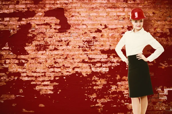 Female engineer woman architect in red safety helmet and red wall — Stock Photo, Image