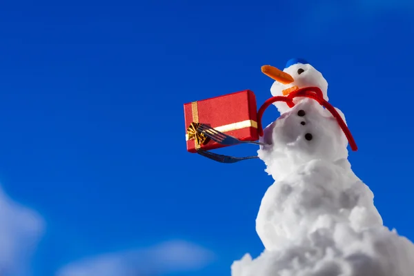 Pequeño muñeco de nieve feliz con caja de regalo de Navidad al aire libre. Temporada de invierno . —  Fotos de Stock