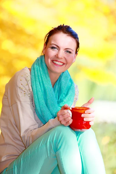 Menina feliz relaxante no parque de outono desfrutando de bebida quente — Fotografia de Stock