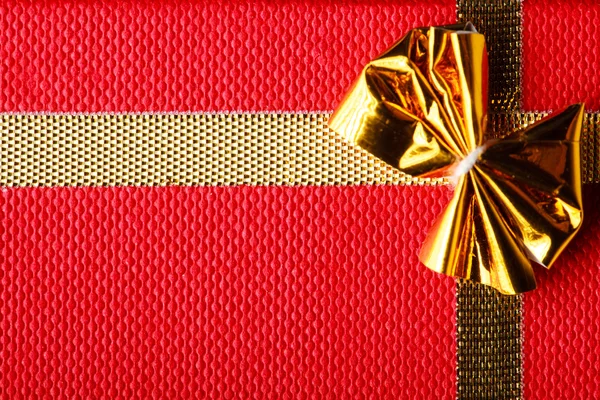 Primer plano de la caja de regalos. Arco dorado sobre fondo rojo —  Fotos de Stock