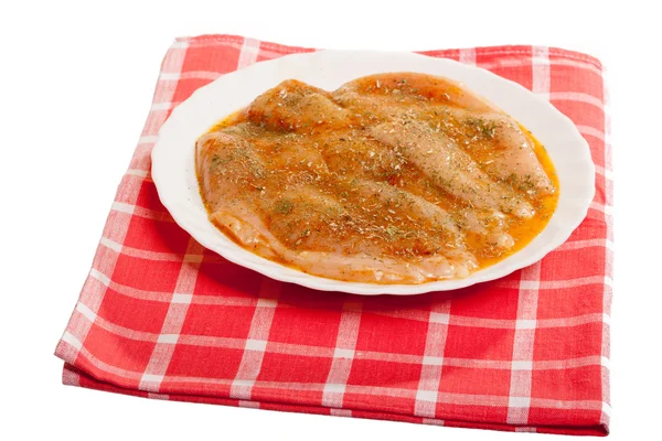 Тарелка сырой маринованной куриной грудки со специями на красной кроватке — стоковое фото