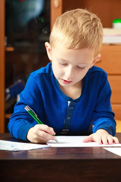 Blond chłopiec dziecko z piórem, pisanie na kartce papieru. W domu. — Zdjęcie stockowe