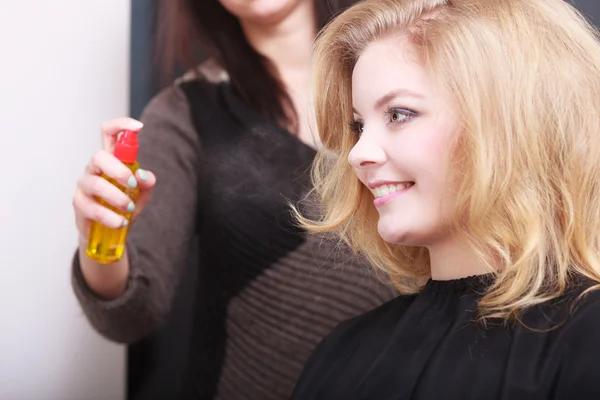 Peluquero con spray para el cabello y chica rubia cliente femenino en el salón —  Fotos de Stock