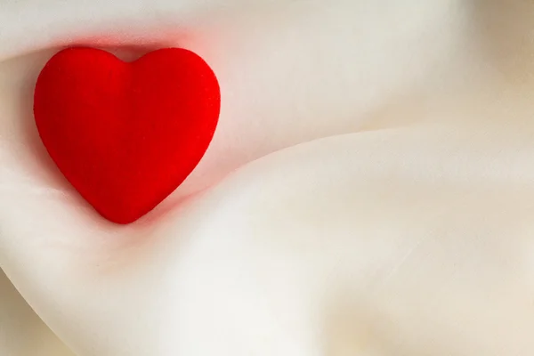Rode houten decoratieve hart op een witte zijde achtergrond. — Stockfoto