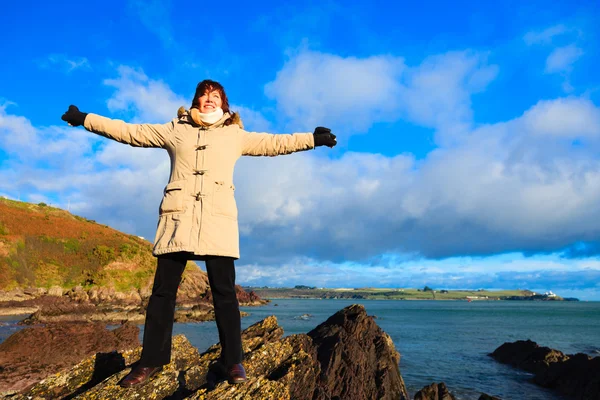 Mujer de pie en el acantilado de roca en el océano, relajante Co. Cork Irlanda —  Fotos de Stock
