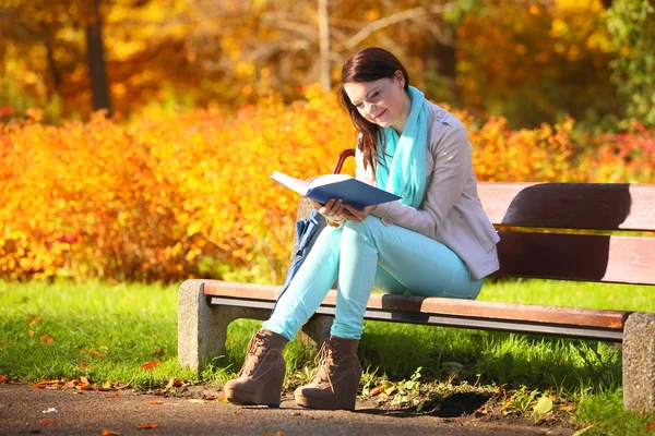 Nuori tyttö rentouttava syksyllä puistossa lukeminen kirja — kuvapankkivalokuva