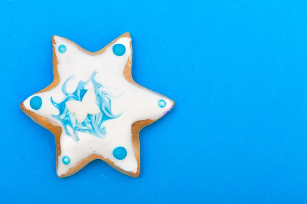 Christmas gingerbread cake star with icing and decoration on blue — Stock Photo, Image