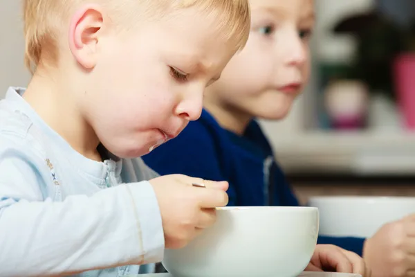 Niños niños comiendo hojuelas de maíz desayuno comida en la mesa — Foto de Stock