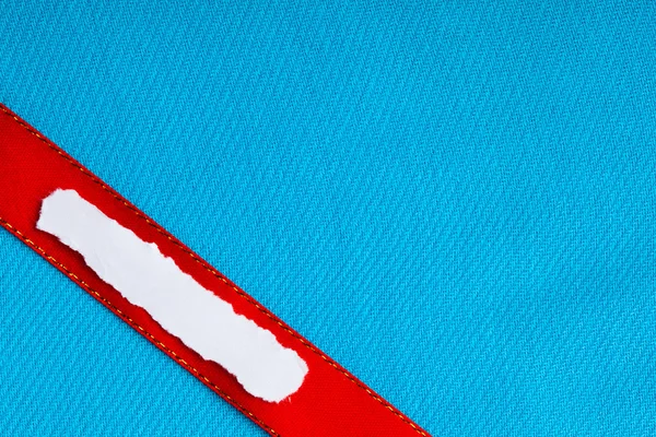 Pedazo de papel de desecho espacio de copia en blanco cinta roja fondo de tela azul — Foto de Stock