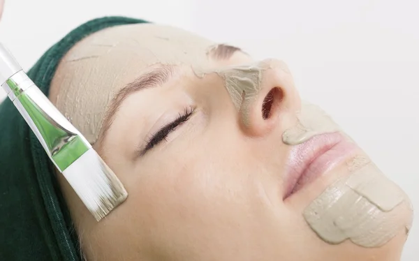 Salone di bellezza. Cosmetico che applica la maschera facciale a faccia di donna . — Foto Stock