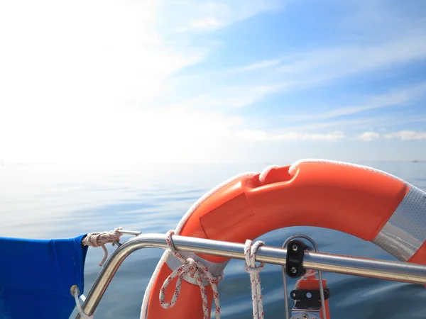 Rescue red lifebuoy on sail and blue sky sea — Stock Photo, Image