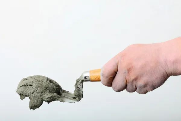 Hand holding a bucket trowel with cement mortar — Stock Photo, Image