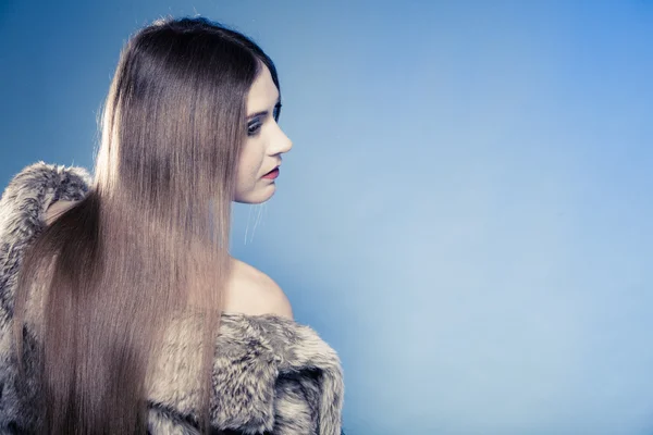 Porträt eines Mädchens mit langen Haaren. Junge Frau im Pelzmantel auf blau. — Stockfoto