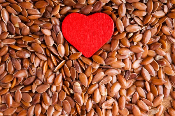 Hälsosam kost. lin frön Linoljefärg som mat bakgrund och röd hjärta — Stockfoto